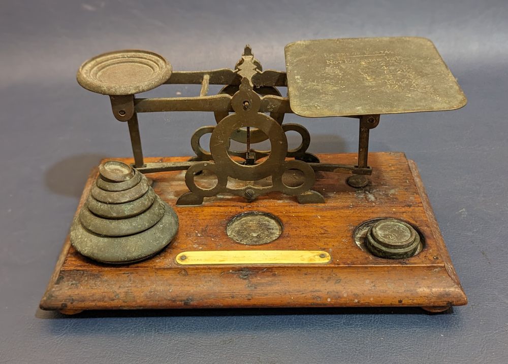 Old brass balance postal scales on mahogany base, 6 disc weights