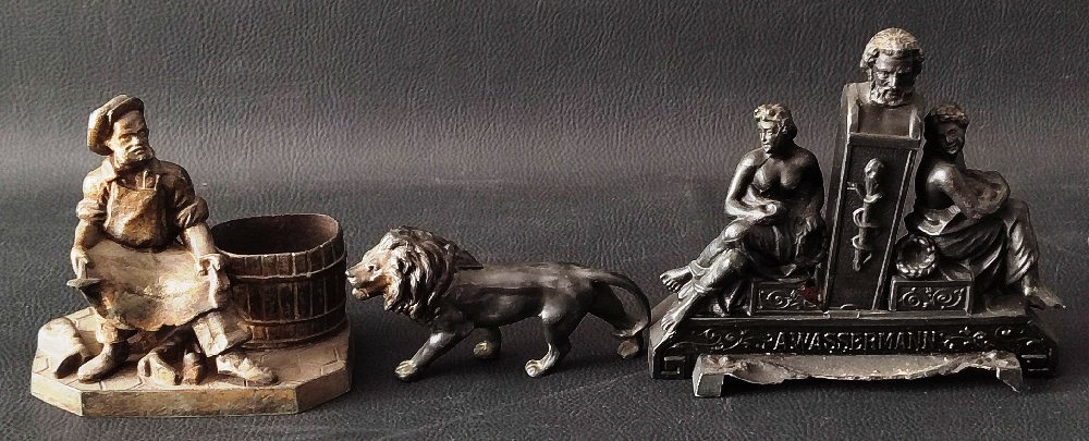 Bronzed figure of a cobbler, lion, and cast iron German figure group